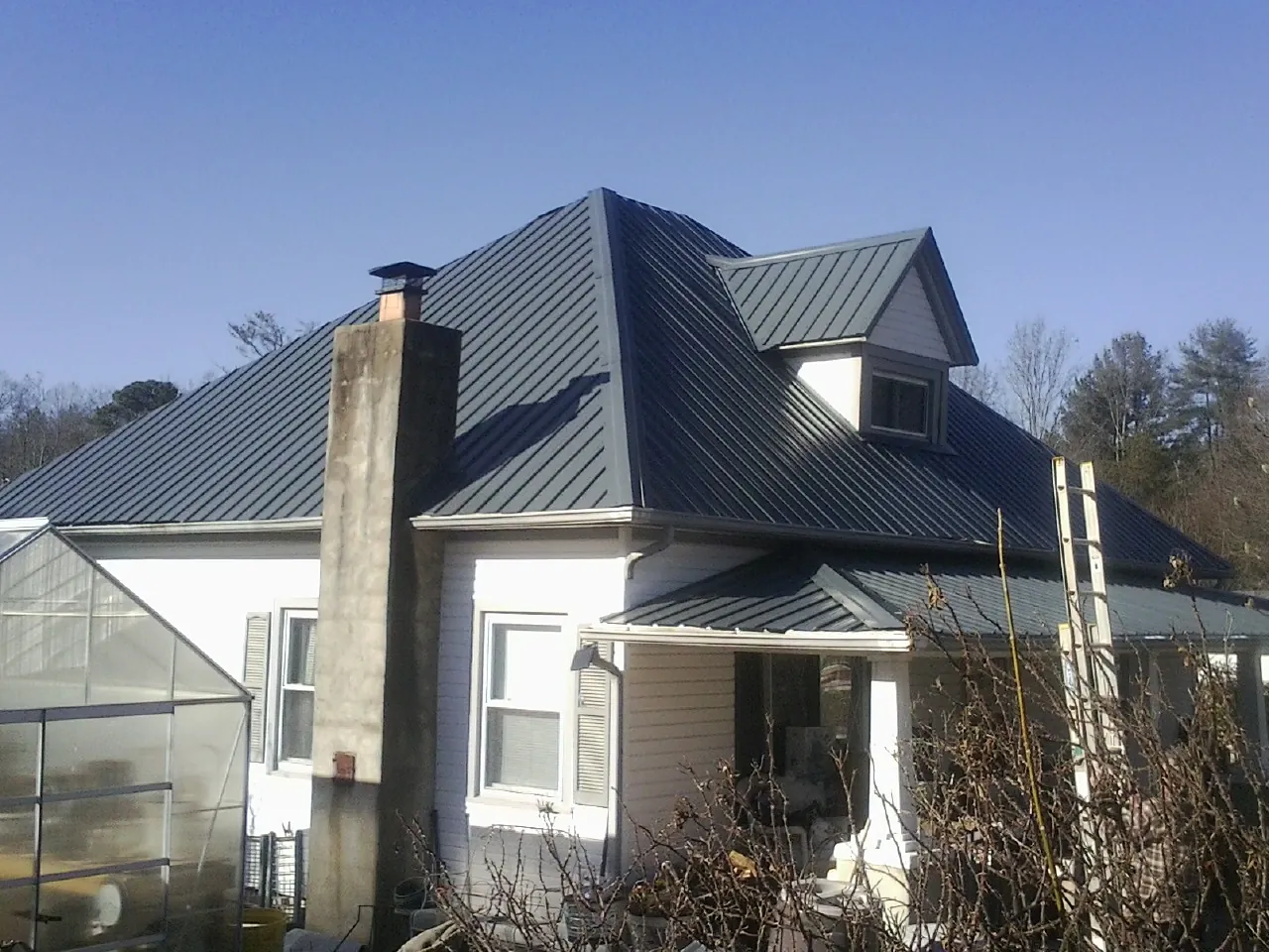 Dark blue standing seam metal roof on a white farmhouse with dormer — Slate & Tile Roof Repair by Roofing Brothers in Taconic