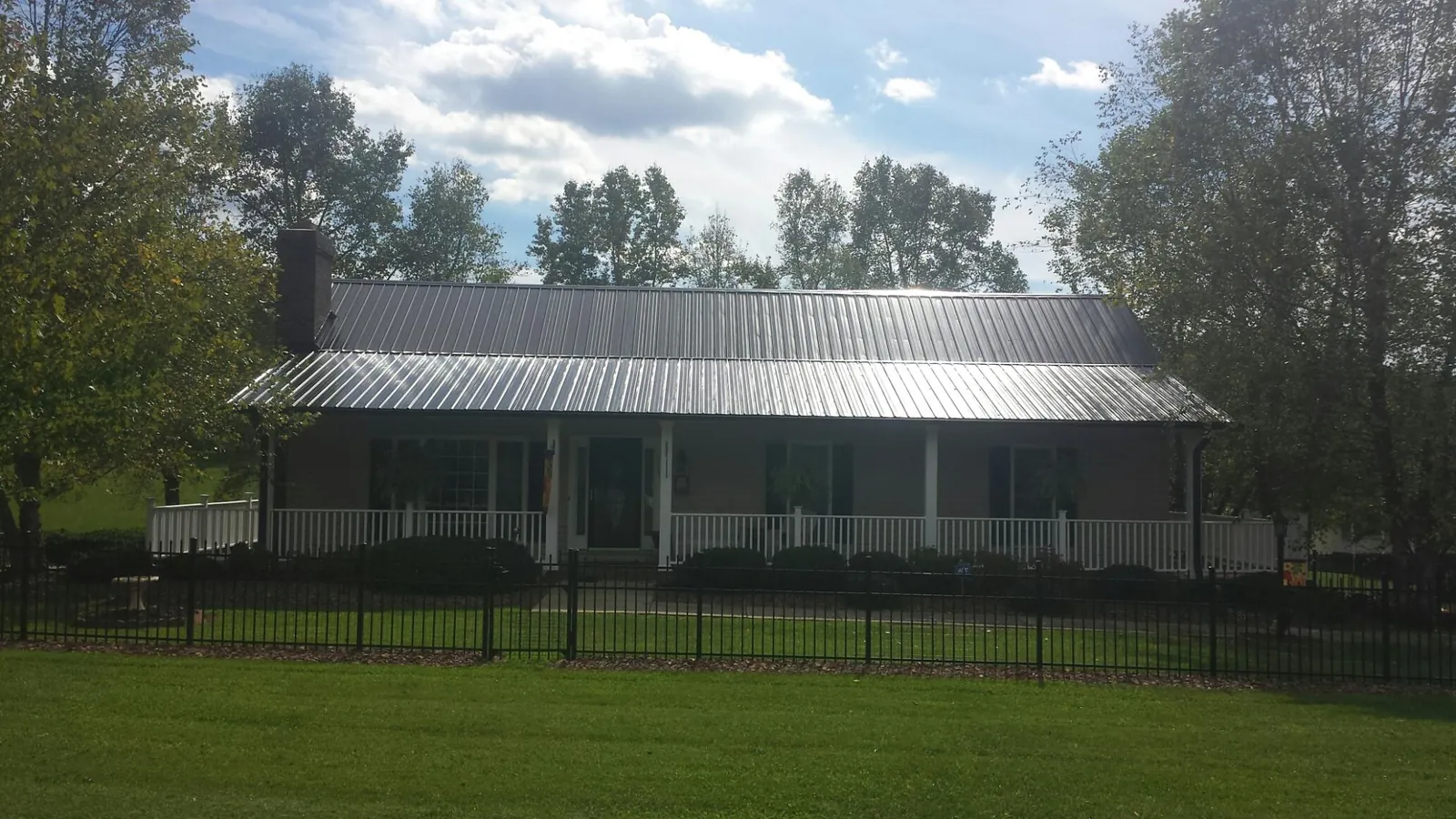 Gray metal roof on a brick ranch with a full width front porch — Gutter Guard Installation work by our crew in Taconic