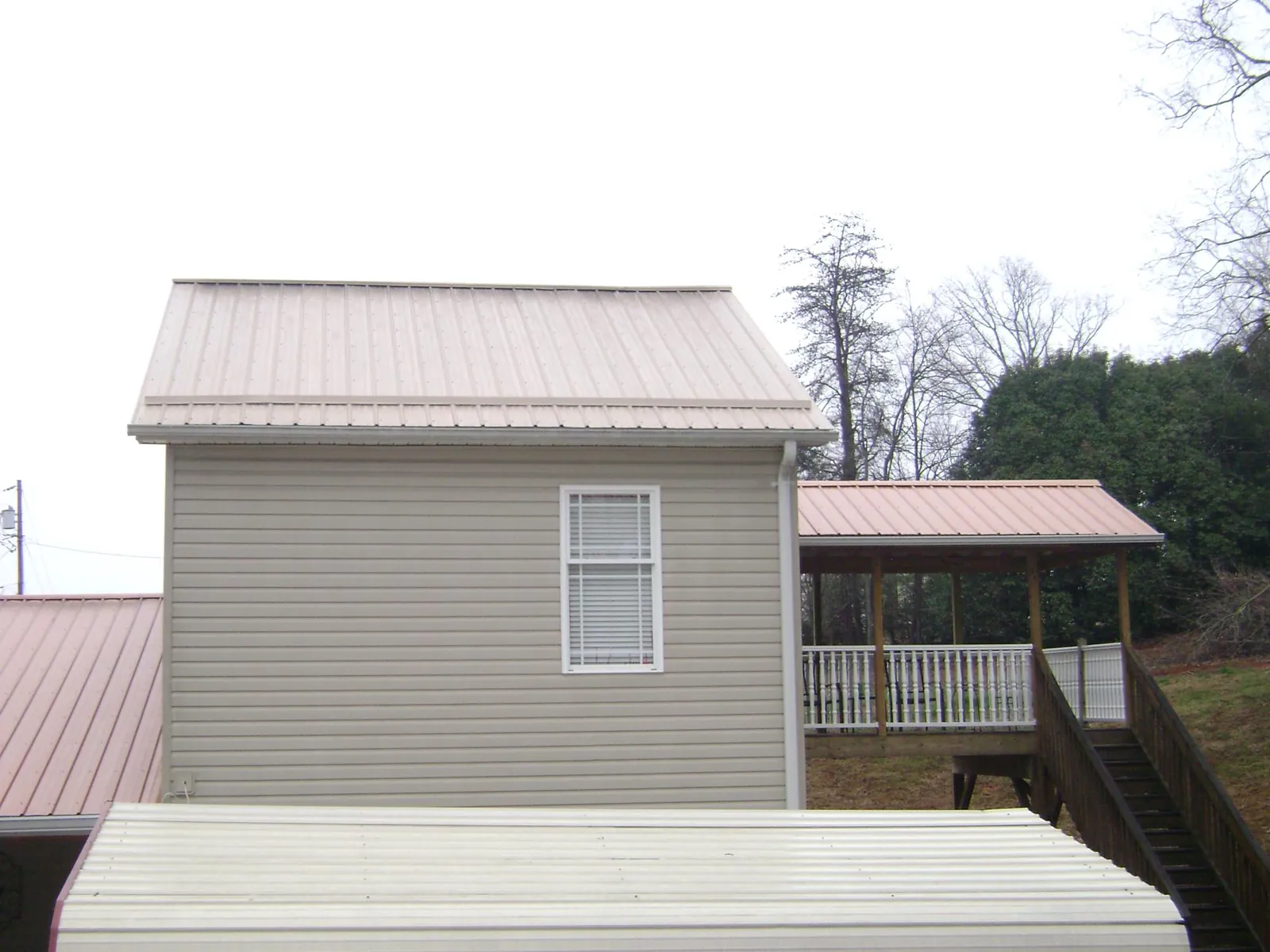 Tan metal roofs on a two story addition and attached porch, from a Roof Replacement job in Taconic