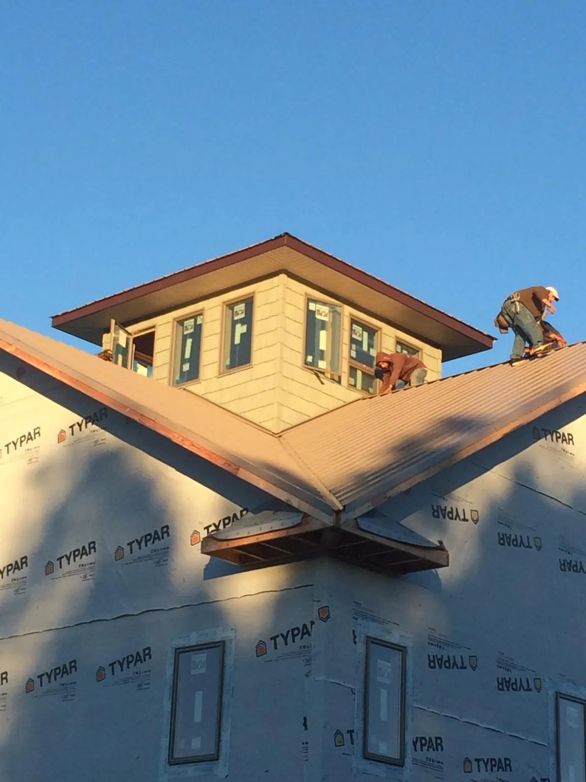 Roofers working around a rooftop cupola on a new metal roof at sunset — Roof Waterproofing in Taconic by Roofing Brothers